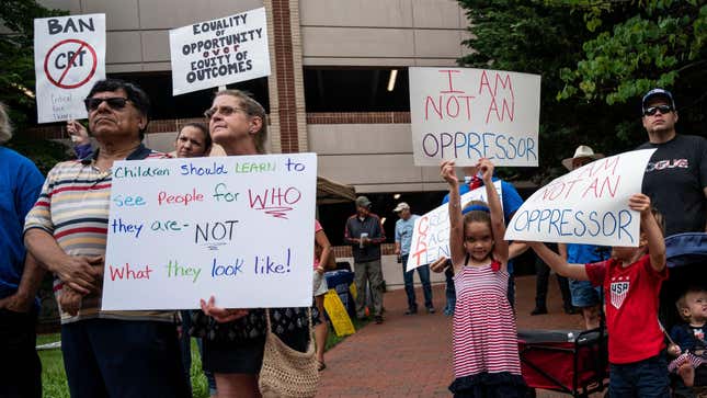 People hold up signs during a rally against “critical race theory” (CRT) being taught in schools at the Loudoun County Government center in Leesburg, Virginia on June 12, 2021.