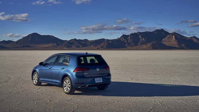 A blue VW golf hatchback parked on a salt flat. 