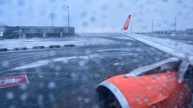 A photo looking out a plane window at snow on a runway. 