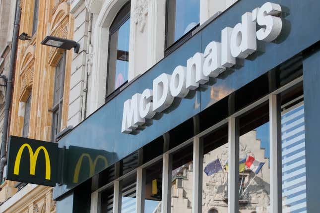 FILE - A French and a European flags are reflected in the shop window of a McDonald&#39;s restaurant in Lille, northern France, Thursday, June 16, 2022 . McDonald’s will become the title sponsor of the French soccer league from July for the next three seasons, the league said on Thursday, March 21, 2024. (AP Photo/Michel Spingler, File)