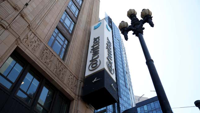 The sign above the street reading @twitter, rising up next to a round-bulbed street lamp.