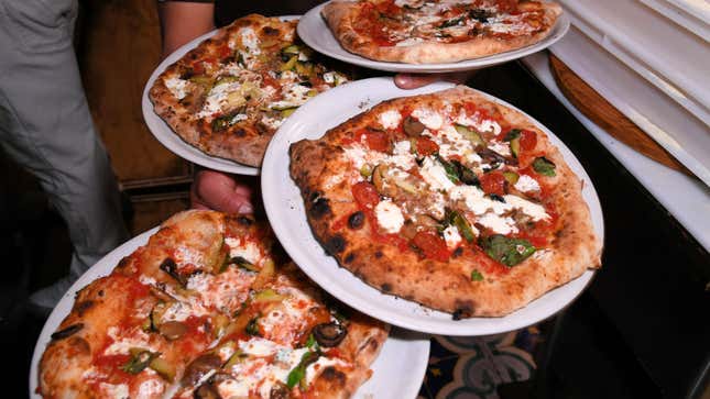 Four Pizzas being carried by a waiter