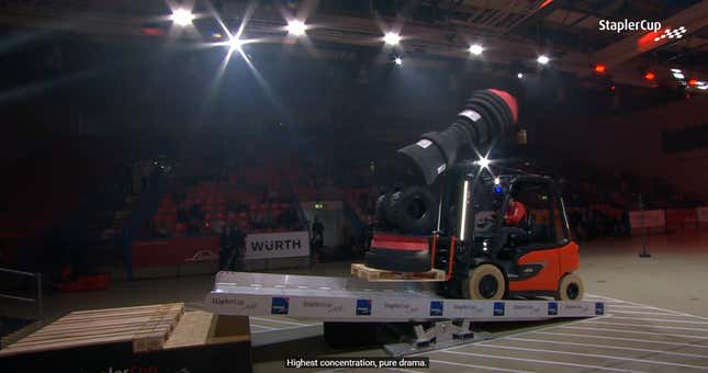 A precariously stacked tower of objects fall during a competitive forklifting event