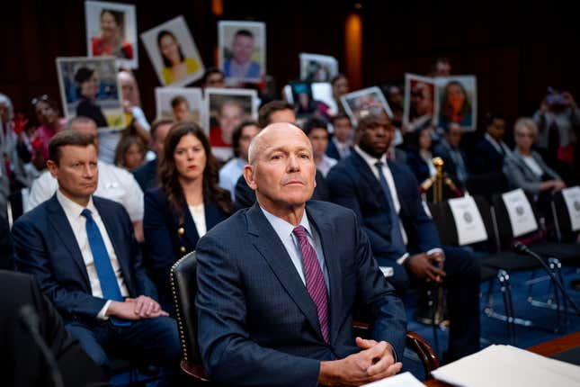 Boeing CEO Dave Calhoun arrives as family members of those killed in the Ethiopian Airlines Flight 302 and Lion Air Flight 610 crashes hold up photographs of their loved ones during a hearing before Congress.