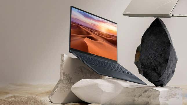 The ASUS Zenbook 14X OLED on a rocks with a beige background