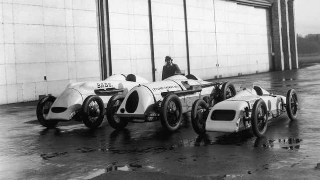 A black and white photo of three vintage racing cars. 