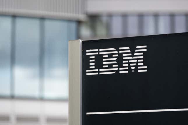 IBM logo on a black sign in front of blurred buildings in the background