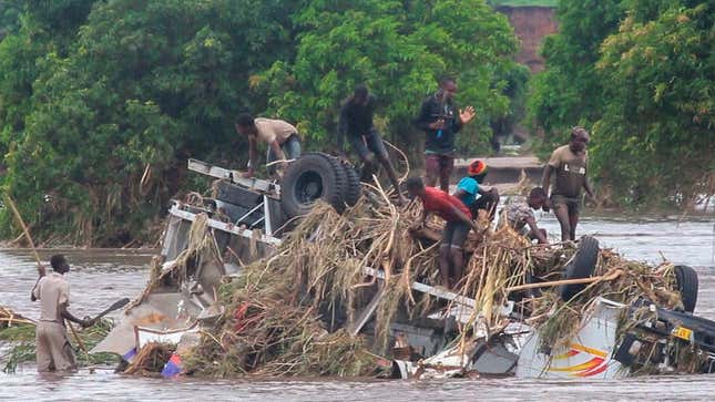 People stand on an overturned vehicle swept by flooding waters in Chikwawa, Malawi, Tuesday Jan. 25.