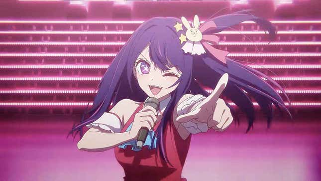 A pop idol sings into a mic and points towards the crowd