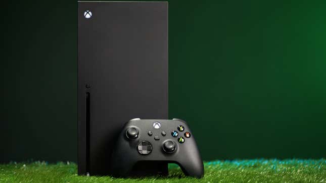 Eine Xbox Series X und ein Controller sitzen auf künstlichem Gras vor einem dunkelgrünen Hintergrund.
