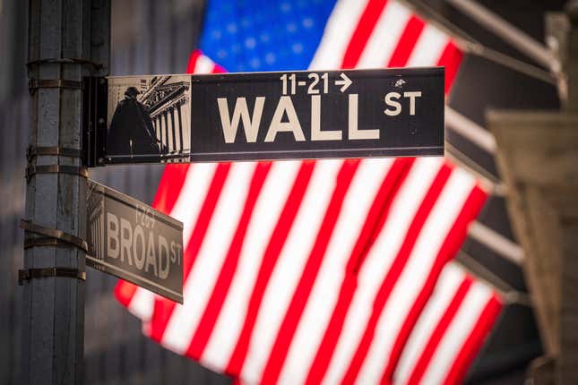 File - The sun shines through American flags flying in front of the New York Stock Exchange at the corner of Wall and Broad Streets in New York City on Nov. 14, 2023. Inflation has cooled enough to get investors looking ahead to a 2024 where interest rates may be on the way down instead of up. (AP Photo/J. David Ake, File)