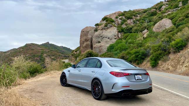 A rear 3/4 shot of the silver C63 that I drove in front of a giant rock 