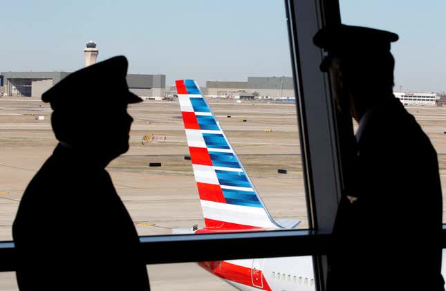 Pilots talk as they look at the tail of an American Airlines aircraft at Dallas-Fort Worth International Airport February 14, 2013. 