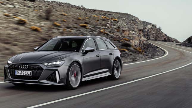 A matte gray RS6 avant driving on a twisty road next to rocks