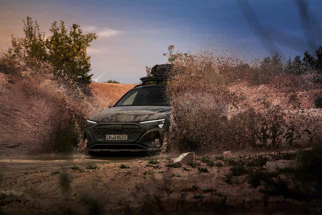 Front 3/4 view of a black Audi Q8 E-Tron driving through mud