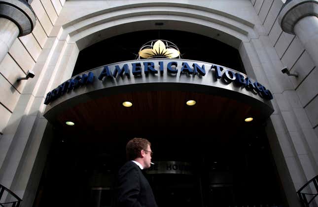 A man in a suit smokes a cigarette outside the entrance to the British American Tobacco headquarters in London.