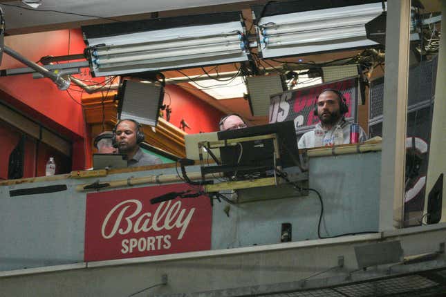 FILE - Cincinnati Reds&#39; Joey Votto, right, sits in the broadcast booth with John Sadak, center right, and Barry Larkin, center left, during a baseball game against the St. Louis Cardinals Wednesday, Aug. 31, 2022, in Cincinnati. Amazon will partner with the Diamond Sports as part of a restructuring agreement as the largest owner of regional sports networks looks to emerge from bankruptcy. Diamond owns 18 networks under the Bally Sports banner. Those networks have the rights to 37 professional teams — 11 baseball, 15 NBA and 11 NHL.(AP Photo/Jeff Dean, File)