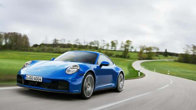 A blue 911 driving on a two-lane road next to grass