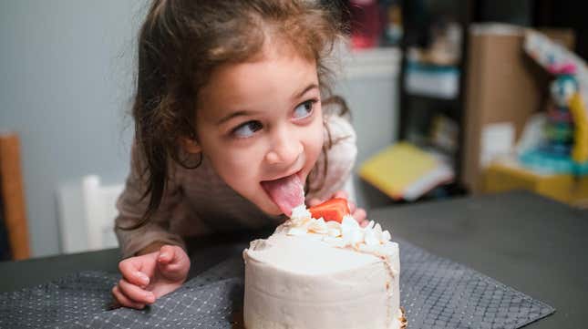 little girl sneaking lick of cake