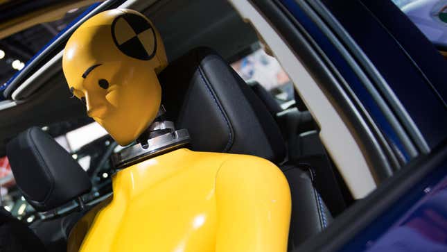 A photo of a yellow crash test dummy strapped into a car. 