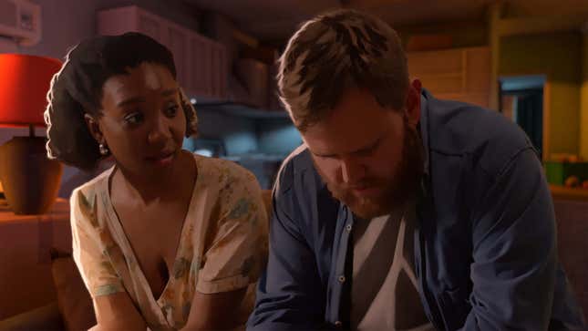 Two people sit on a couch in a kitchen in As Dusk Falls.