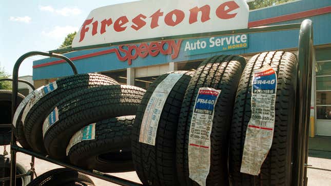 A photo of tires on a rack outside an auto shop. 