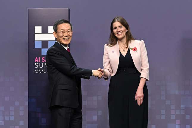 Lee Jong-ho and Michelle Donelan shaking hands in front of a purple backdrop with the AI Summit symbol