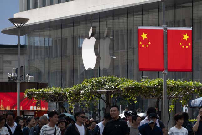 business new tamfitronics people pass in front of an apple store with the logo in front with chinese flags displayed