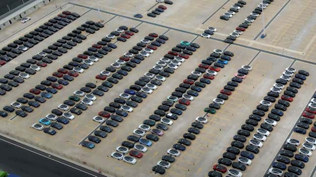 A photo of a parking lot full of new Teslas including some painted bright colors