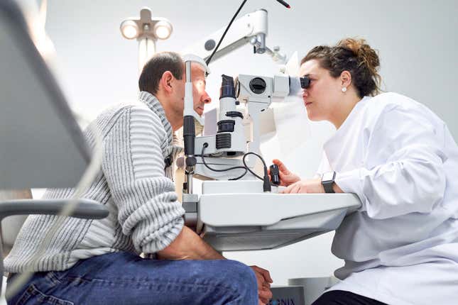 Female ophthalmologist examining male patient in ophthalmology clinic with autorefractometer, examination of eyesight. - stock photo