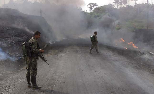 FARC rebels walk by a burning oil pipeline they sabotaged.
