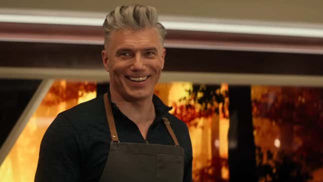 Captain Pike, wearing an apron, smiles.