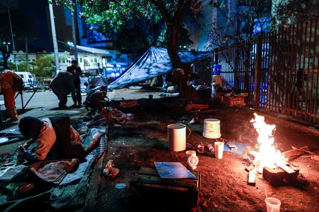 Unhoused people light a fire to stay warm during a cold night in Sao Paulo, Brazil, Thursday, July 29, 2021.