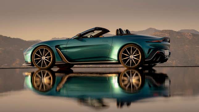 A photo of the side view of an Aston Martin V12 Vantage Roadster with its reflection in water below. 