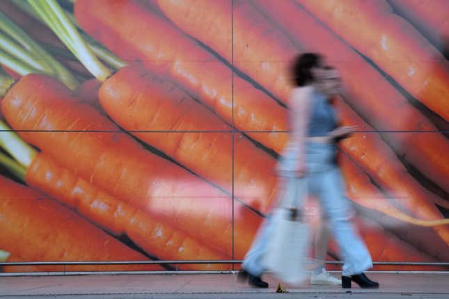 FILE - Shoppers walk past a large poster outside a supermarket in London, on June 10, 2023. Inflation in the U.K. held steady at 4% in January as lower food prices helped offset an increase in energy costs, official figures showed Wednesday, Feb. 14, 2024. The reading was better than expected as most economists expected inflation to rise modestly to around 4.2%. The Office for National Statistics said the monthly drop in food prices of 0.4% was the first since September 2021. (AP Photo/Alastair Grant)