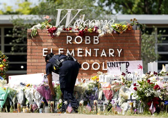 A police officer lays flowers outside Robb Elementary School in the town of Uvalde, Texas, the United States, May 27, 2022.
