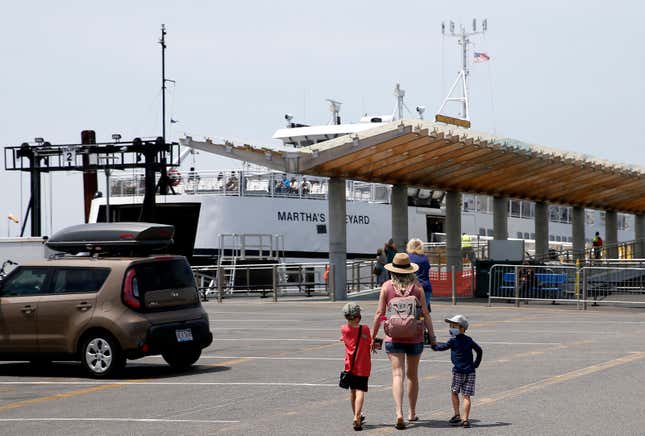 Two children and an adult approach a ferry boarding area hand in hand. 