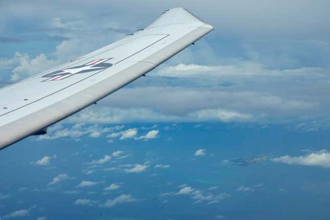 FILE - A U.S. P-8A Poseidon reconaissance plane flies near Chinese structures and buildings on the man-made Fiery Cross Reef at the Spratlys group of islands in the South China Sea are seen on March 20, 2022. The U.S. 7th Fleet says a Navy P-8A Poseidon flew through the Taiwan Strait dividing China from the self-governing island democracy and close U.S. partner on Wednesday, April 17, 2024, a day after the U.S. and Chinese defense chiefs held their first talks since Nov. 2022 in an effort to reduce regional tensions. (AP Photo/Aaron Favila, File)