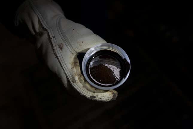 A worker shows a cup of oil extracted from hundreds of meters underground with the steam-assisted gravity drainage system at Cenovus&#39; Sunrise oil facility northeast of Fort McMurray on Thursday, Aug. 31, 2023. (AP Photo/Victor R. Caivano)