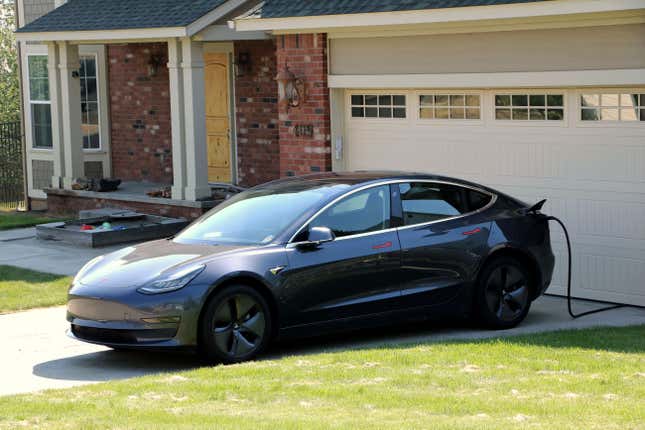 A grey Model 3 charging in its owner's driveway