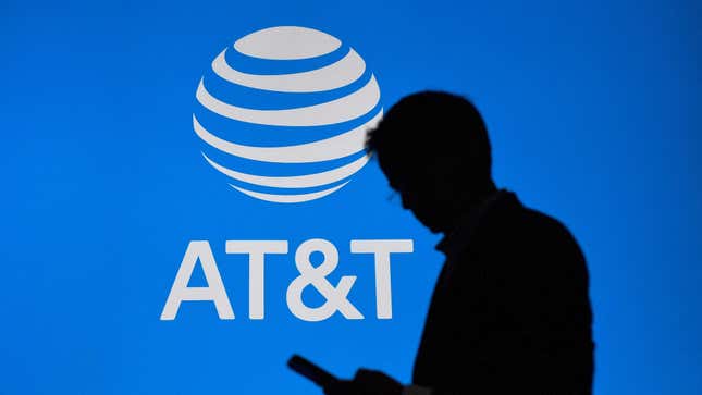 An image of a man checking his phone against the backdrop of an AT&T logo.