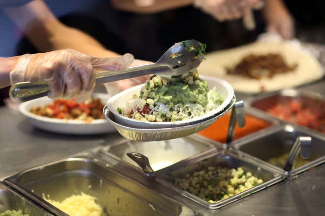 Un employé du restaurant Chipotle préparant un bol à burrito.