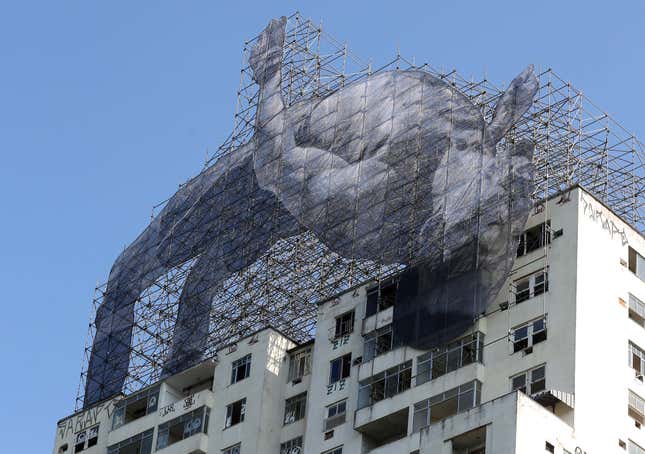 Image for article titled Street artist JR honors a Sudanese athlete who’s missing the Olympics with a towering mural in Rio