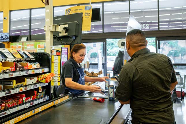 A cashier rings in grocery store products at a register.