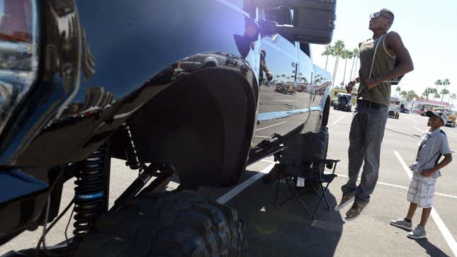 Jaedan Griffin, 12 of Los Angeles, watches his step-brother Derrick Brown, 17 of Long Beach, hop as he attempts to take a peek inside a raised 2009 Ford F-250 Super Duty truck at the Ford Truck Jam at the Long Beach Arena in Long Beach CA. Sunday October 6, 2013.