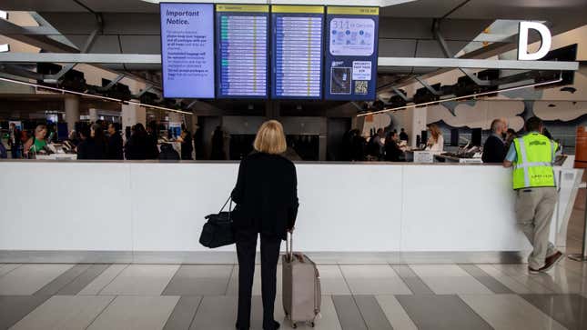 A photo of a passenger looking up at an airport departure board. 