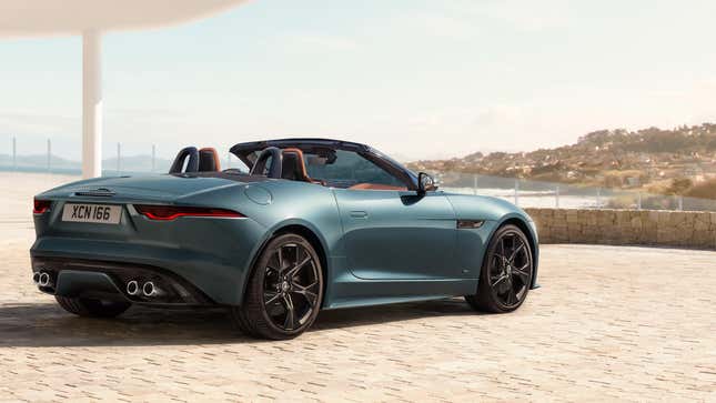 A blue Jag F Type parked on brick in front of a coastline