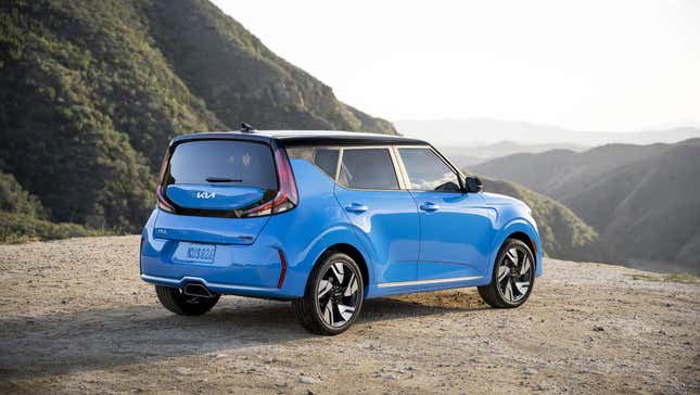 A bright blue Kia Soul parked on dirt near a mountain vista