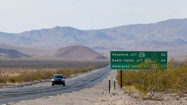 A car drives down a highway through the desert 