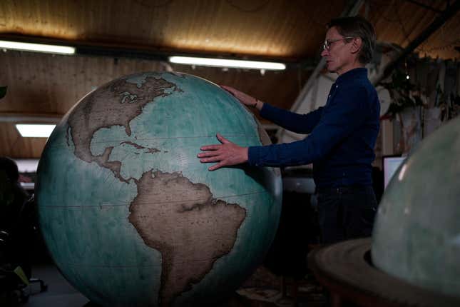 Peter Bellerby, the founder of Bellerby &amp; Co. Globemakers, holds a globe at a studio in London, Tuesday, Feb. 27, 2024. Globes in the age of Google Earth capture the imagination and serve as snapshots of how the owners see the world and their place in it. Peter Bellerby made his first globe for his father, after he could not find one accurate or attractive enough. In 2008, he founded Bellerby &amp; Co. Globemakers in London. His team of dozens of artists and cartographers has made thousands of bespoke globes up to 50 inches in diameter. The most ornate can cost six figures. (AP Photo/Kin Cheung)